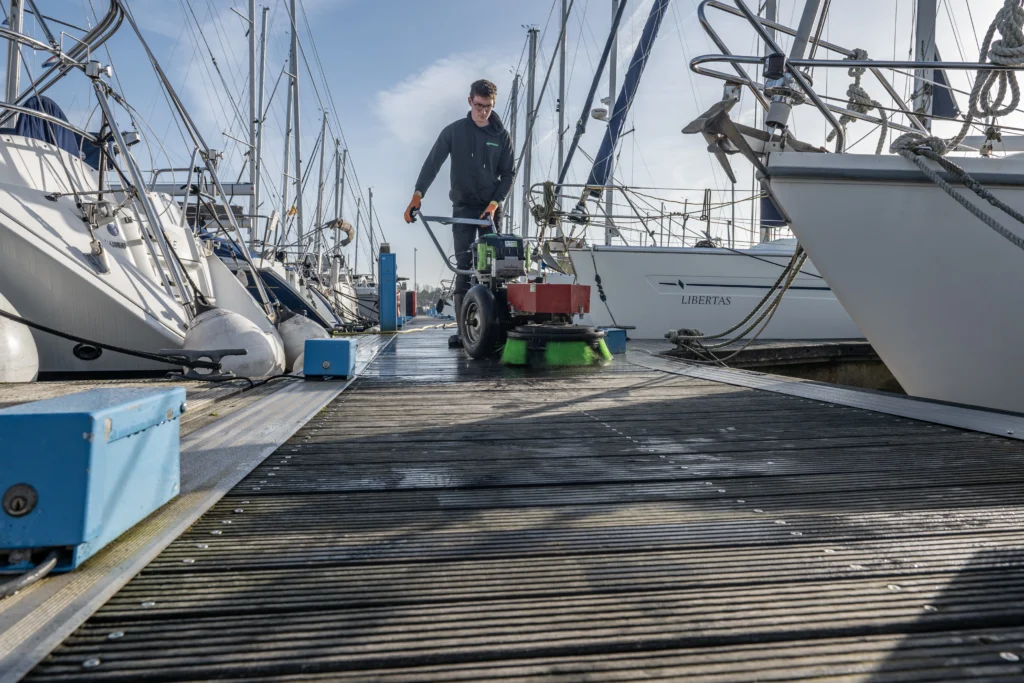 Groene aanslag op een houten steiger verwijderen met een borstelmachine